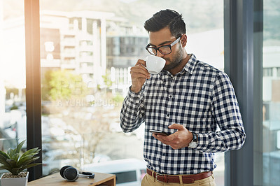 Buy stock photo Shot of a young businessman using his cellphone while having coffee