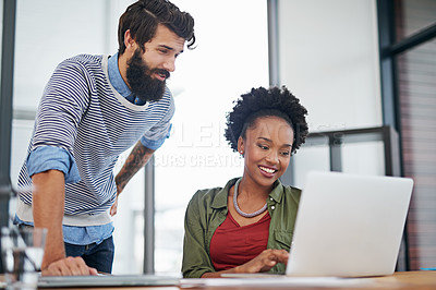 Buy stock photo Cropped shot of two young creatives working together on a laptop in an office