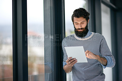 Buy stock photo Cropped shot of a young creative using a digital tablet in an office