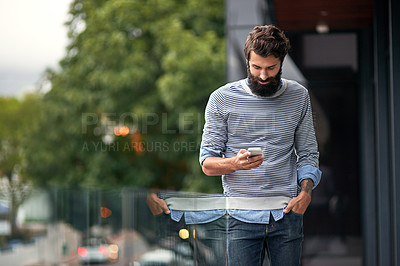 Buy stock photo Cropped shot of a young creative texting on a cellphone outside