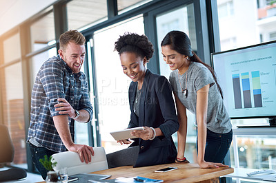 Buy stock photo Shot of a team of young colleagues using a digital tablet together at work