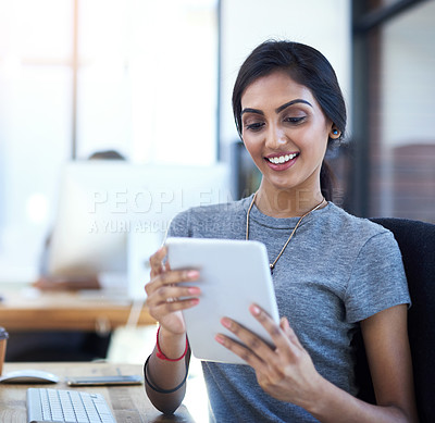 Buy stock photo Shot of a young businesswoman using a digital tablet at her work desk