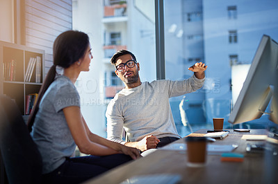 Buy stock photo Shot of a young businessman explaining an idea to his coworker at work