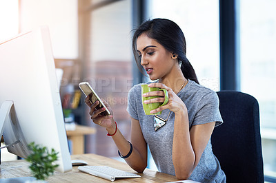 Buy stock photo Business, computer and Indian woman with phone in office for coffee break, scroll or social media chat. Pc, smartphone and gen z administration intern with tea cup for newsletter app, text or blog