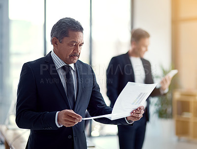 Buy stock photo Shot of a mature businessman going over some paperwork