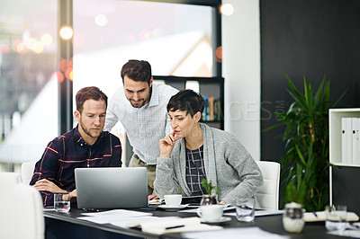 Buy stock photo Cropped shot of a group of businesspeople working together on a laptop in a modern office