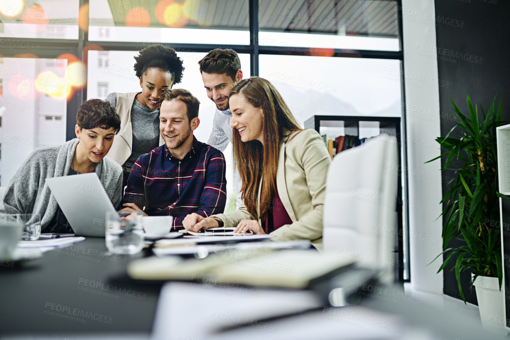 Buy stock photo Cropped shot of a group of businesspeople working together on a laptop in a modern office