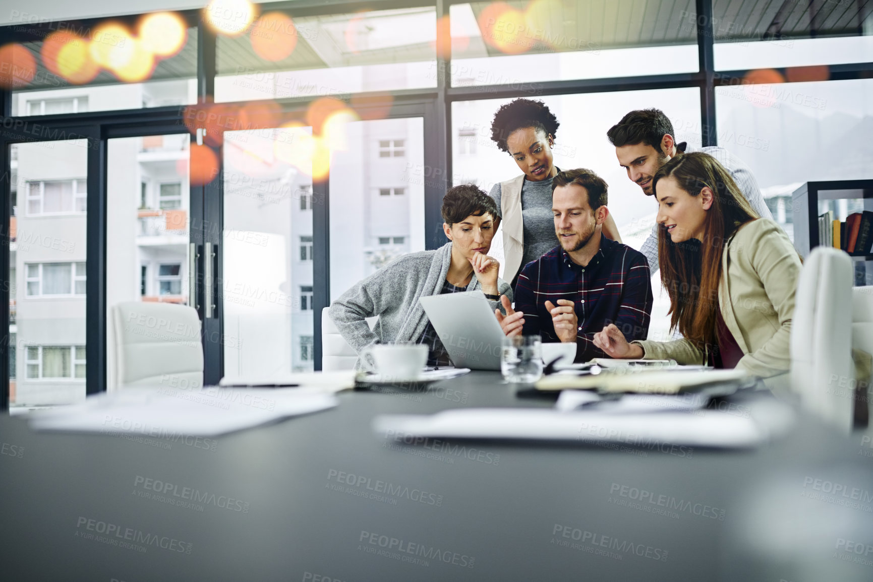 Buy stock photo Cropped shot of a group of businesspeople working together on a laptop in a modern office