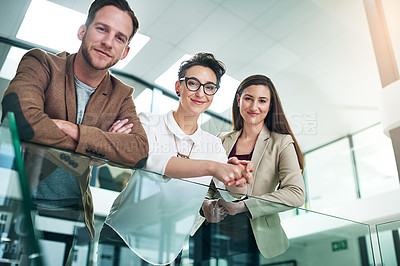 Buy stock photo Portrait of a group of colleagues leaning on a railing together in a large modern office