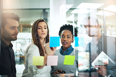 Buy stock photo Cropped shot of coworkers using sticky notes on a glass wall during a meeting