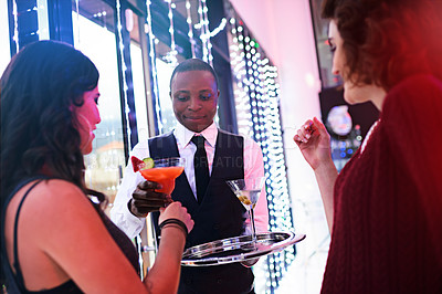 Buy stock photo Shot of a waiter serving two women cocktails at a party
