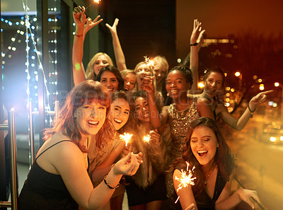 Buy stock photo Shot of a group of girlfriends having fun with sparklers on a balcony on a night out