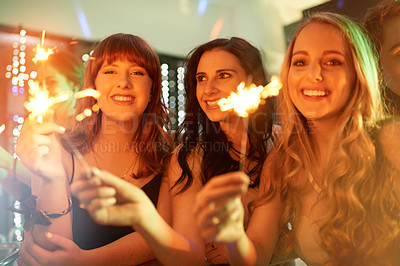 Buy stock photo Group, friends and celebration with sparklers, women and cheerful at party, night out and fireworks. Happy, event and smile for new year, birthday and club in disco, lights and entertainment