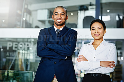 Buy stock photo Portrait of two young businesspeople standing with their arms folded in the office