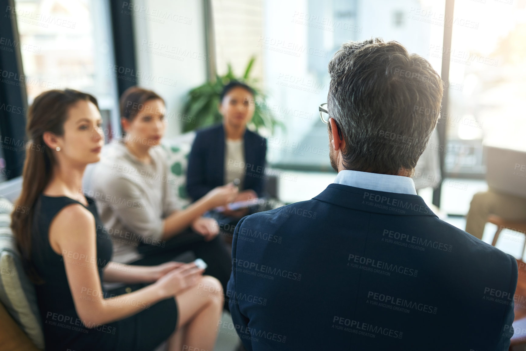 Buy stock photo Shot of a group of businesspeople listening to their manager during a meeting