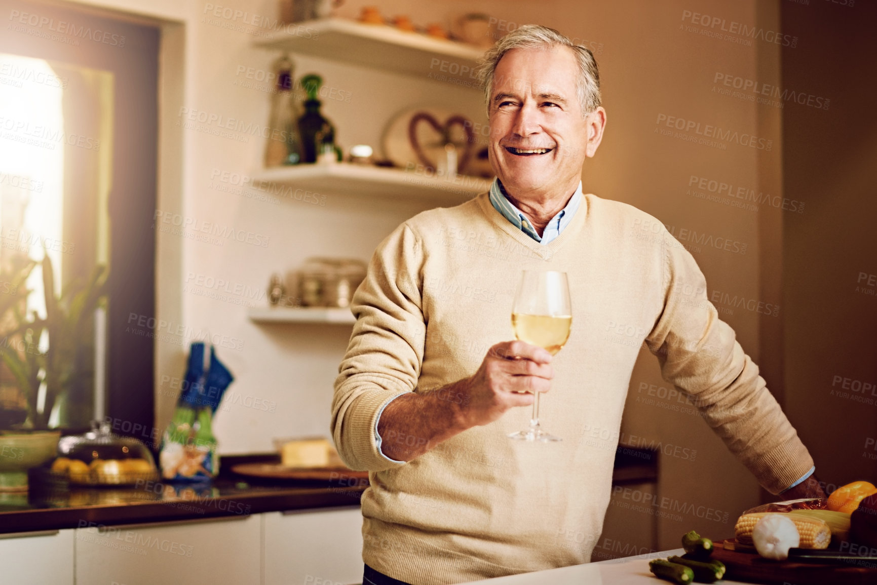 Buy stock photo Shot of a senior man enjoying a glass of wine while preparing dinner in his kitchen