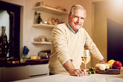 Buy stock photo Shot of a senior man enjoying a glass of wine while preparing dinner in his kitchen
