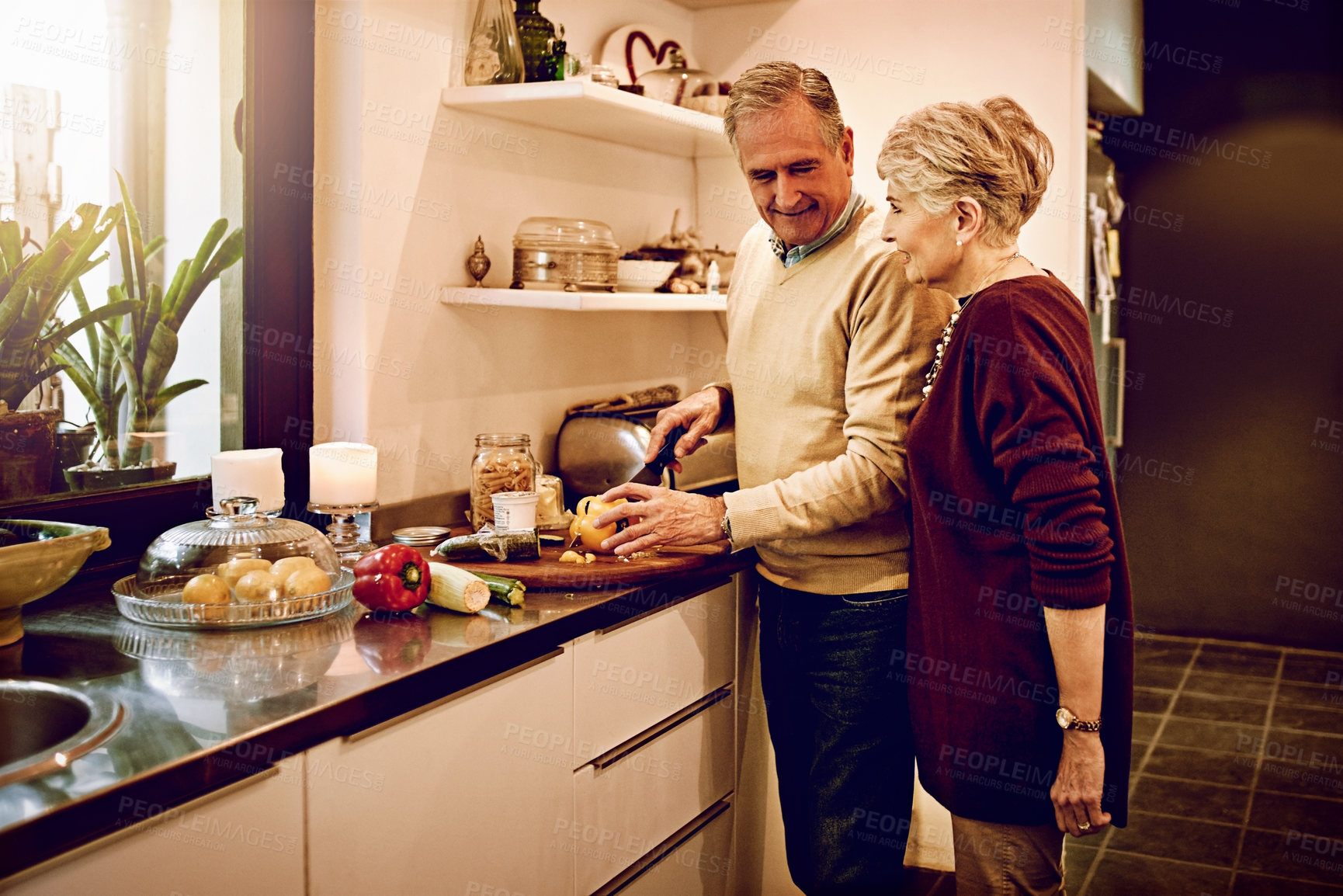 Buy stock photo Cropped shot of an elderly woman watching her husband prepare a meal in their kitchen