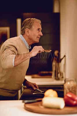 Buy stock photo Shot of an elderly man cooking a meal in his kitchen