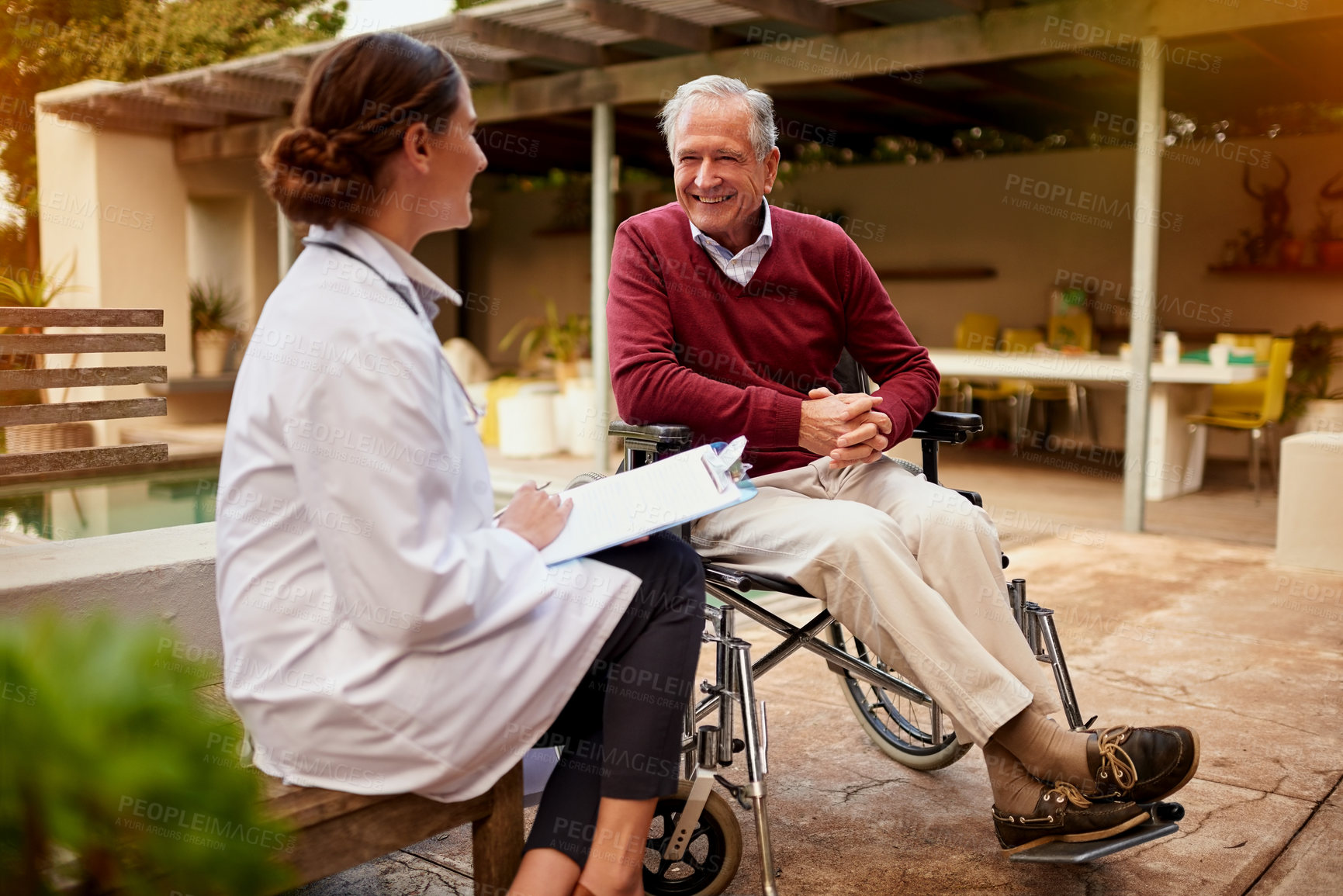 Buy stock photo Shot of a young doctor and her elderly patient talking while sitting outside