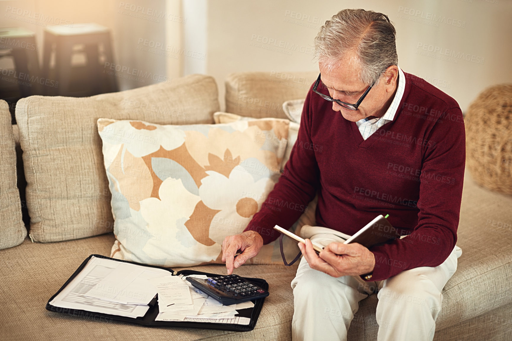 Buy stock photo Shot of a senior man working out a budget while sitting on the living room sofa