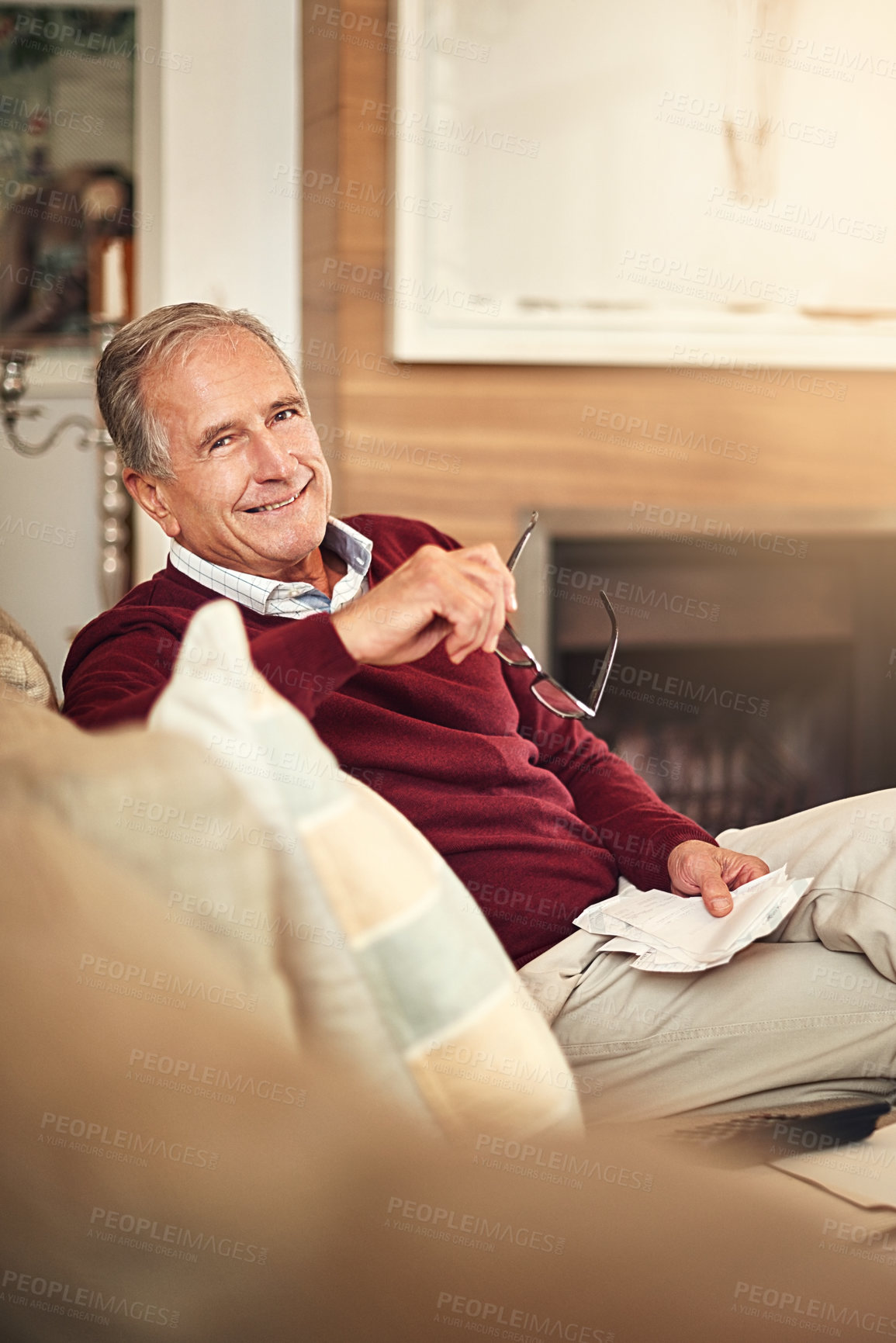 Buy stock photo Portrait of a senior man sitting at home holding receipts