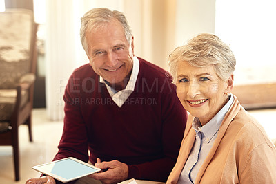 Buy stock photo Portrait of a senior couple sitting in their living room while using a digital tablet