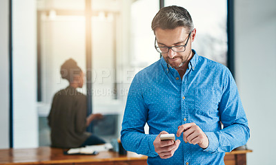 Buy stock photo Cropped shot of a businessman texting on a cellphone in an office
