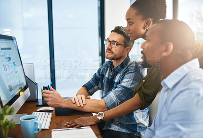 Buy stock photo Cropped shot of three businesspeople working around a computer in the office
