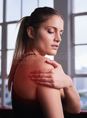 Buy stock photo Shot of a sporty young woman holding her injured shoulder that's highlighted in red