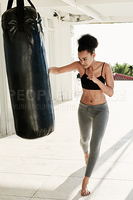 Buy stock photo Shot of a sporty young woman working out with a punching bag outside