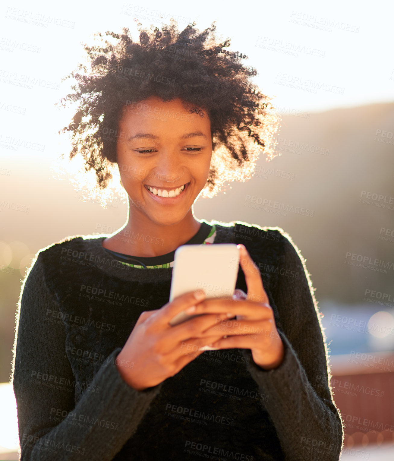 Buy stock photo Shot of an attractive young woman sending a text message while walking outside