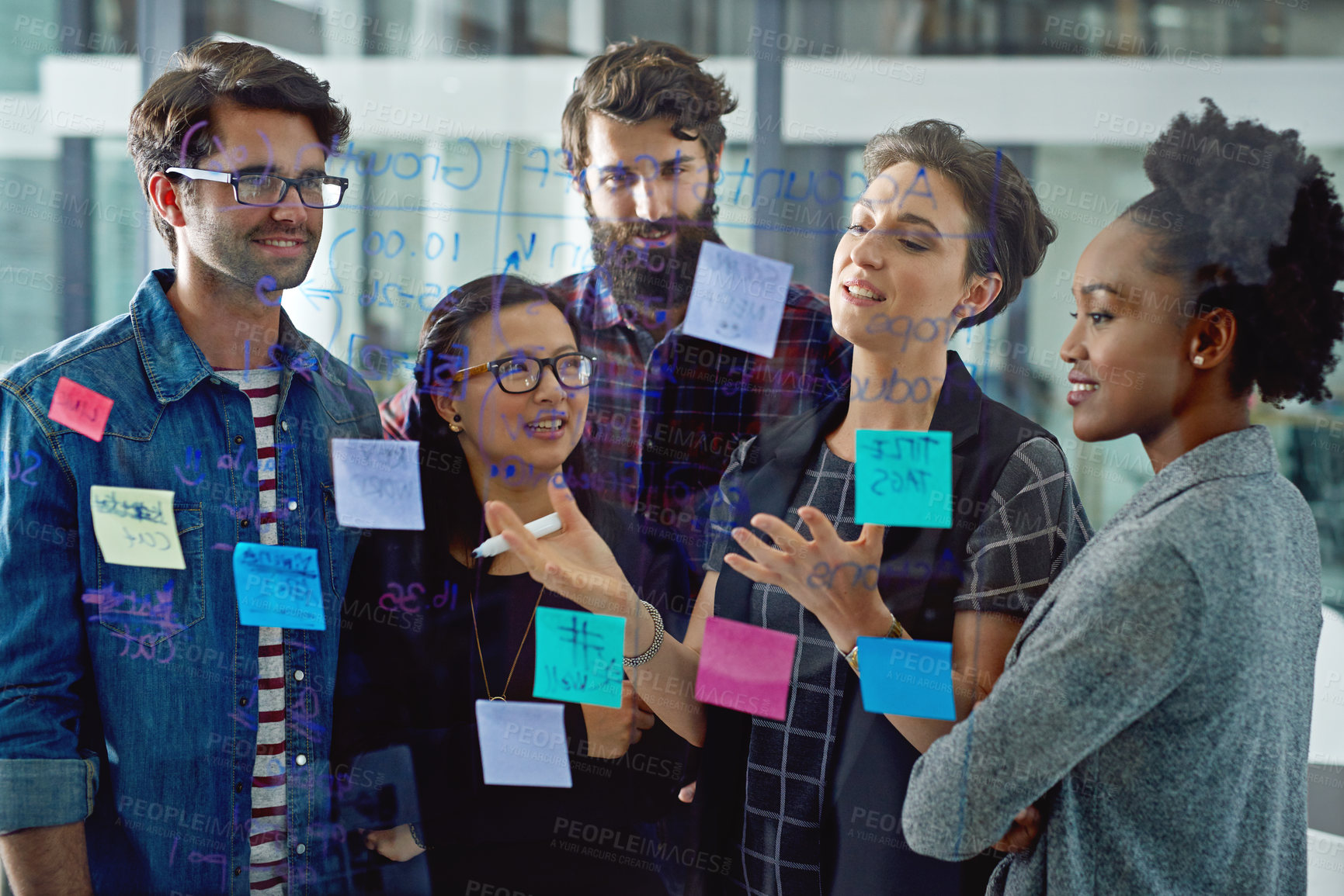 Buy stock photo Shot of a group creative businesspeople working on a glass wall in the office