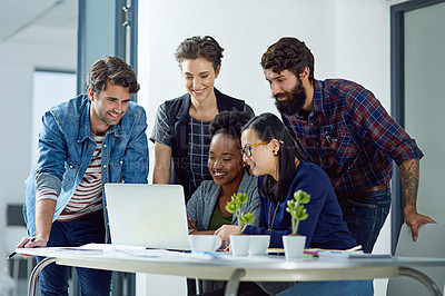 Buy stock photo Shot of a group of creative businesspeople gathered around a laptop in the office