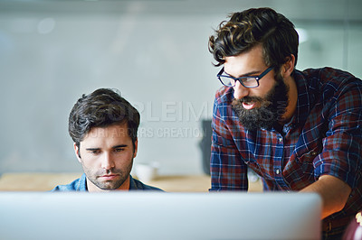 Buy stock photo Shot of two young businessmen working on a computer in the office