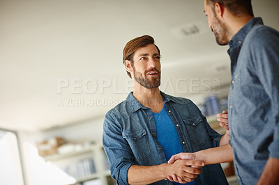 Buy stock photo Shot of two businessmen shaking hands together while standing in an office