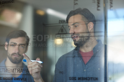 Buy stock photo Shot of young businessman brainstorming on a glass wall while standing in an office
