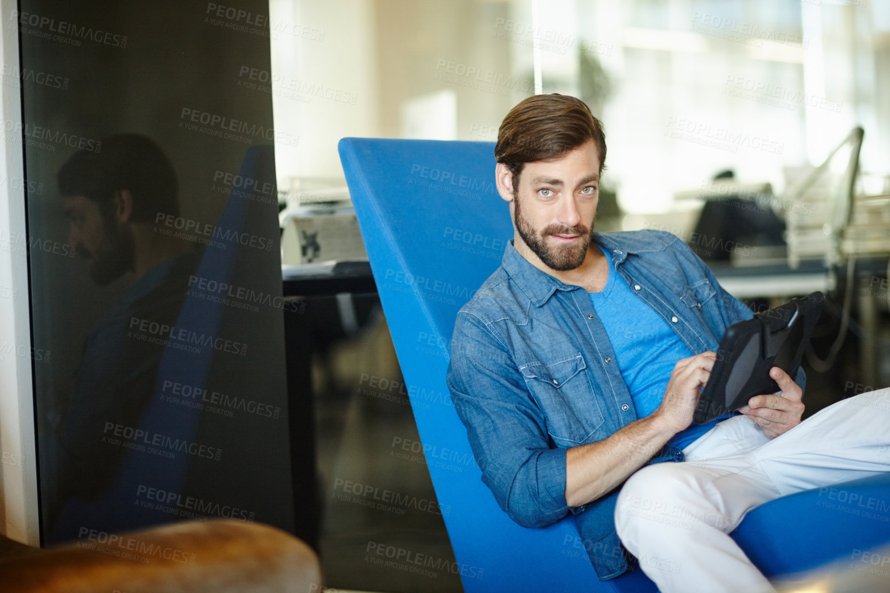 Buy stock photo Portrait of a young businessman using a digital tablet while sitting in an office