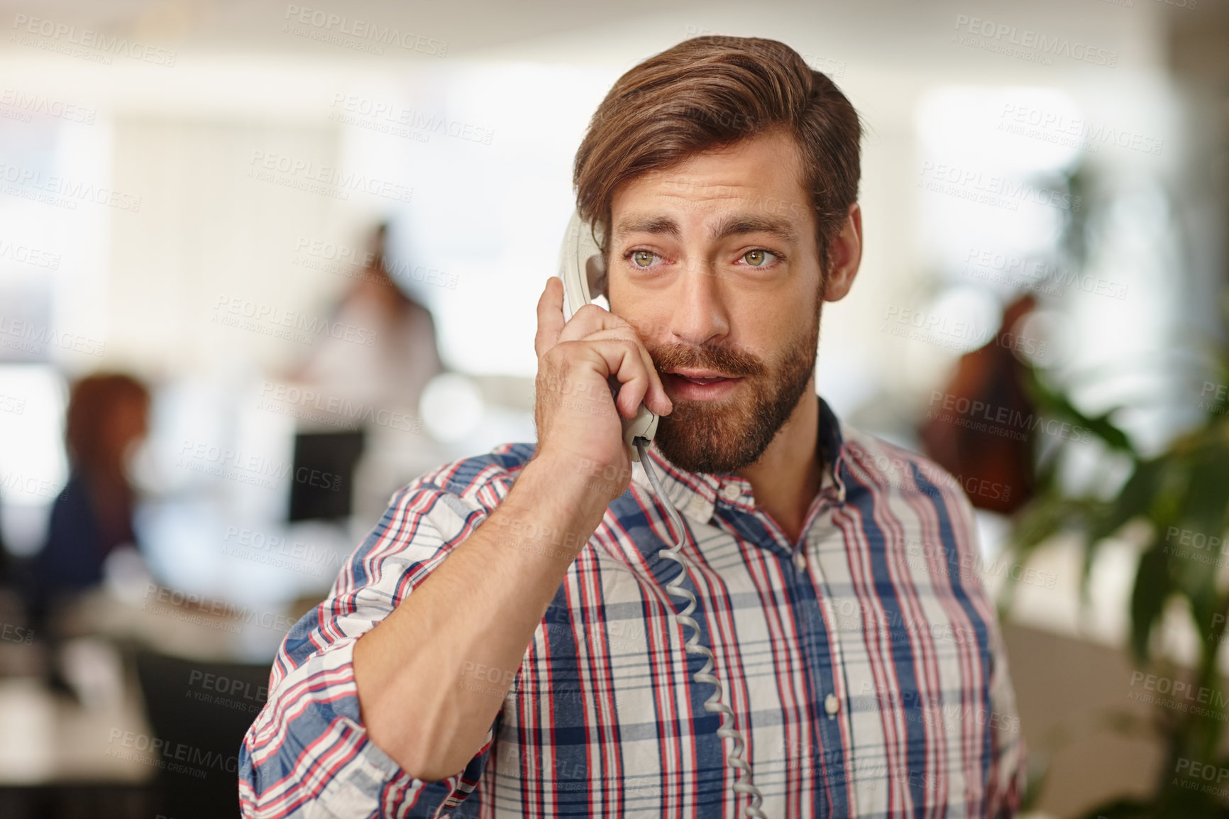 Buy stock photo Cropped shot of a young businessman talking on a phone in an office