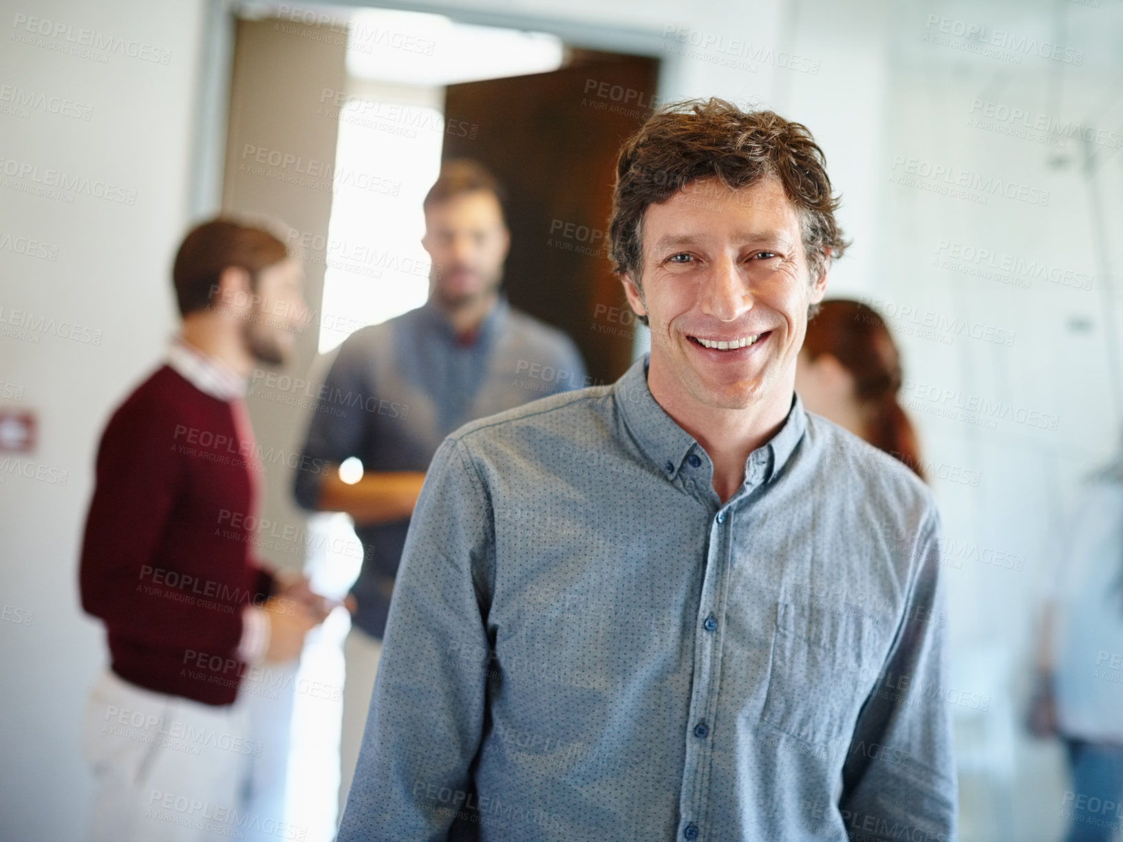 Buy stock photo Portrait of a businessman standing in the office with his colleagues in the background