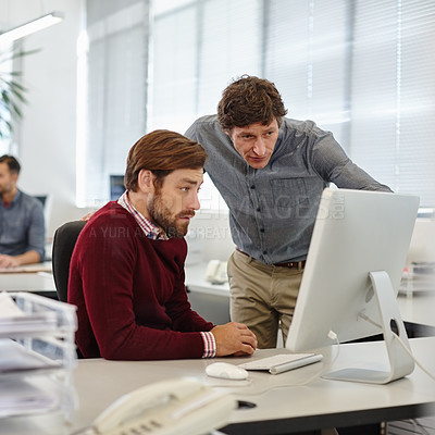 Buy stock photo Shot of a businessman and his colleague working together on a computer in the office