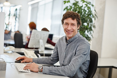 Buy stock photo Portrait of a businessman working on his computer in the office with his colleagues in the background