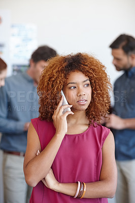 Buy stock photo Shot of a businesswoman using her cellphone in the office with her colleagues in the background