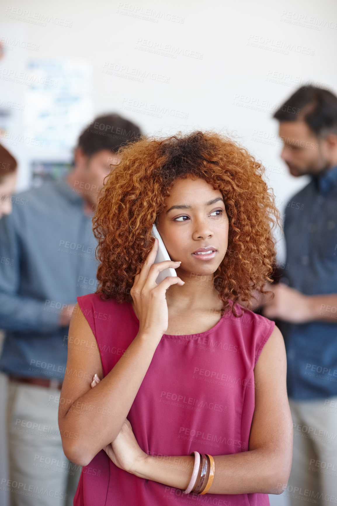 Buy stock photo Shot of a businesswoman using her cellphone in the office with her colleagues in the background