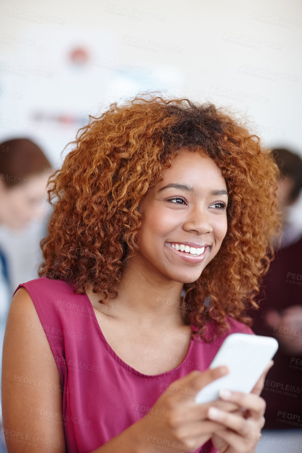 Buy stock photo Shot of a businesswoman using her cellphone in the office with her colleagues in the background