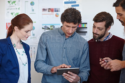 Buy stock photo Shot of a group of businesspeople looking at a tablet together in the office