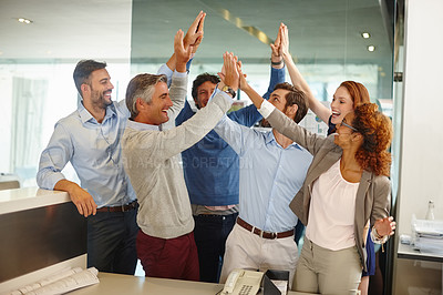 Buy stock photo Shot of a group of colleagues giving each other a high five at work