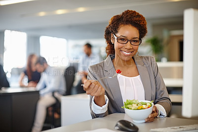 Buy stock photo Portrait of a young businesswoman having a salad during her lunch break at her desk