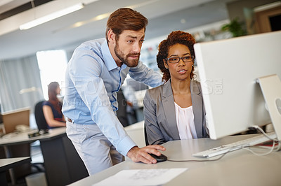 Buy stock photo Shot of two coworkers using a computer together at work