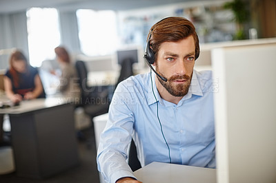 Buy stock photo Shot of a man working with a headset and computer at his desk